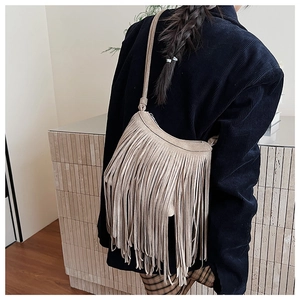Détail d'un sac à bandoulière kaki à franges montrant les longs glands sur daim