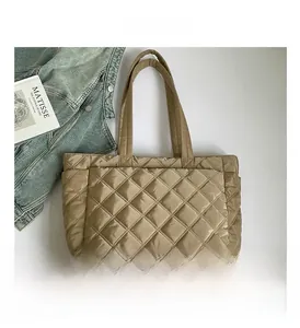 Detailed macro view of khaki quilted down tote bag fabric with elegant diamond stitch pattern