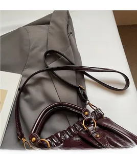 Detailed macro view of glossy burgundy pleated tote bag with detachable leather shoulder strap