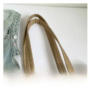 Close-up of quilted khaki tote bag with dual handles and detailed stitching on fabric