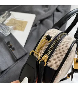 Detail van beige geweven handtas met zwart lederen rand en gouden metalen sluiting