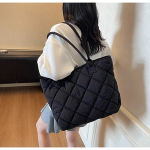 Detail view of a black quilted puffer tote bag shown on model for size and capacity