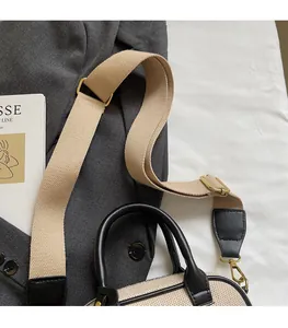Detailopname van de verstelbare stoffen schouderband van een beige en zwarte crossbodytas