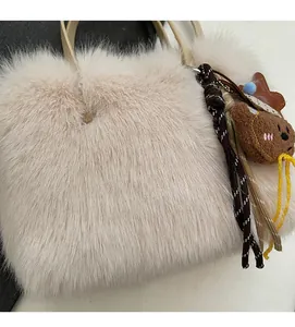 Gros plan d'un sac en fausse fourrure avec poignées en cuir et charm ours mignon