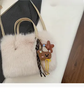 Détail du sac bandoulière en fausse fourrure avec broderie d'ours et breloques en cuir