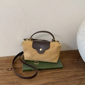 Detailed shot of yellow suede and brown leather patchwork bag with gold metal zippers