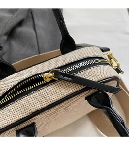 Detail van de gouden rits en leren trekker op beige canvas crossbody handtas