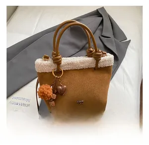 Dettaglio borsa a secchiello in camoscio marrone con bordo in shearling e ciondoli
