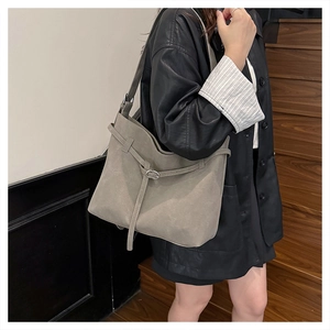 Minimalist grey frosted leather tote bag with silver buckle worn on a shoulder