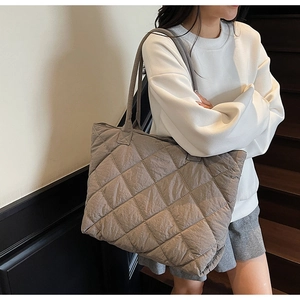 Detail of quilted stitching and khaki large capacity tote bag shown on a model's shoulder