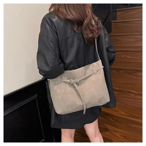 Detail of grey frosted leather tote bag with silver buckle on a stylish wooden staircase