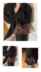 Detail of dark brown glossy tote bag showing pleated texture and gold metal ring hardware