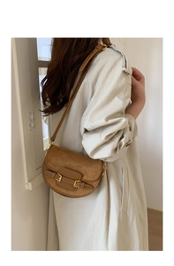 Detail of caramel brown suede saddle bag with dark leather trim and vintage metal buckles