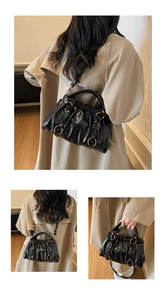 Detail view of black pleated leather handbag featuring four decorative gold metal rings