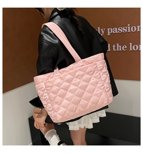 Pink quilted tote bag with diamond pattern and padded straps shown in a street style view