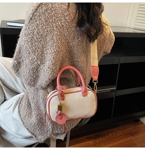 Detail van een canvas crossbodytas met roze lederen bies en brede stoffen riem