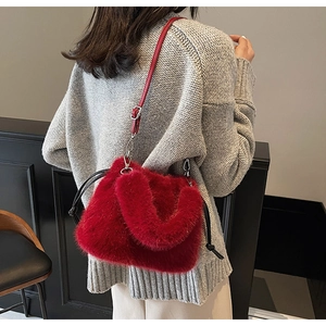 Détail du sac seau en peluche rouge avec cordon et bandoulière porté par un mannequin