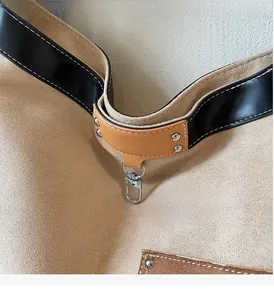 Close-up of silver metal hooks and contrasting leather straps on a suede tote bag