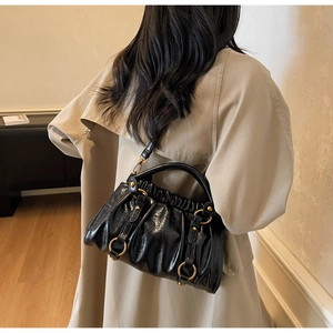 Detail view of black pleated vintage tote bag with gold hardware worn over an apricot coat