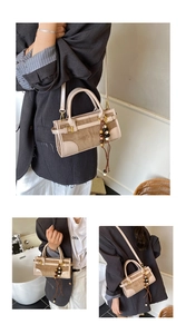 Detail of retro shoulder bag featuring beige leather, brown suede, and beaded pendant