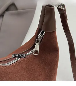 Detailed macro view of the smooth silver zipper and brown suede texture on the bucket bag