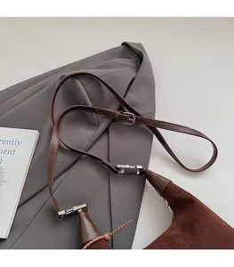 Close-up of brown suede bucket bag featuring adjustable slim leather strap and silver buckle
