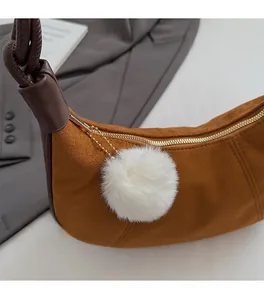 Detail of brown suede crescent bag with dark leather knotted handle and white fur charm