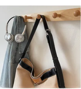 Detail of suede tote bag with contrast stitching, adjustable strap and lifestyle props