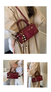 Detail of burgundy patent leather Boston bag with vintage wooden bead charm and shoulder strap