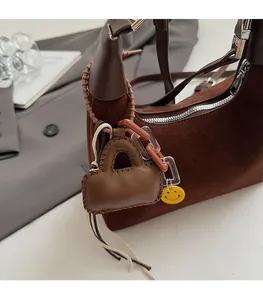 Detail of dark brown suede bucket bag featuring leather tassel and smiley face charm