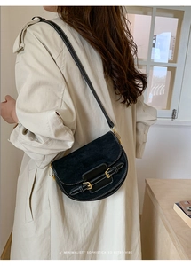 Detalle de bolso silla retro de ante negro con costuras blancas y correas de hebilla