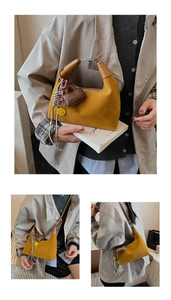 Detail of mustard yellow suede bucket bag with stylish charms and brown leather handle
