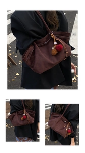 Détail d'un sac cabas en similicuir marron foncé avec un pendentif pompon décoratif