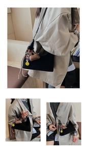 Detail of black suede hobo bucket bag with yellow smiley face and woven tassel pendants