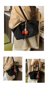 Détail du sac cabas vintage en daim noir avec pompon coloré et doubles bandoulières