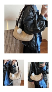 Detail of beige crescent bag featuring brown braided strap and fluffy white plush charm