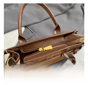 Detail shot of the gold metal zipper and premium leather texture on a brown handbag