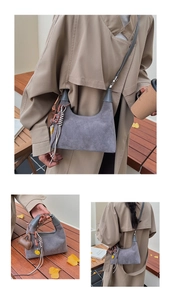 Detail of grey suede bucket bag featuring tassels and heart charm in an outdoor setting