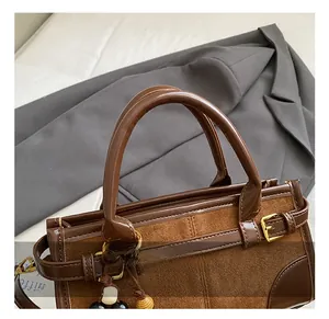 Detail of cylindrical leather handles and metal buckles on brown retro baguette bag