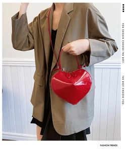 Dettaglio di una borsa in vernice rossa a forma di cuore tenuta da una modella