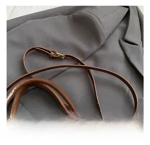 Detail of adjustable strap and golden metal buckle on dark brown patchwork boston bag