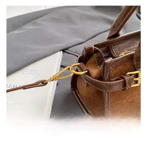 Detail showing smooth brown leather and caramel suede texture with gold metal buckles