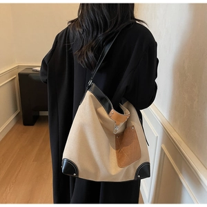 Detail view of suede contrast pocket and leather trim on canvas bucket tote bag