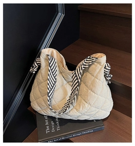 Detailed texture of quilted tote bag with black and white striped knot shoulder strap