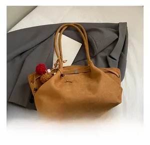 Détail d'un sac cabas en daim marron avec pampille vintage et fines bandoulières