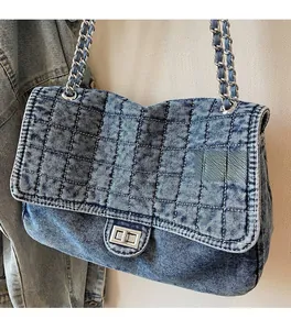 Close-up of blue denim crossbody bag with diamond quilting and silver chain strap