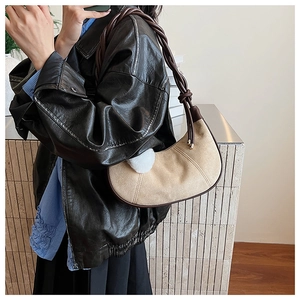 Détail du sac croissant en toile avec poignée en cuir tressé et pompon blanc