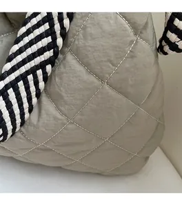 Detail of light green quilted tote bag featuring woven black and white rope handles