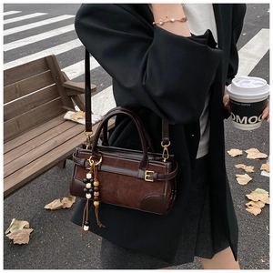 Detail of vintage dark brown baguette bag with beaded tassel in an outdoor setting