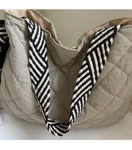 Close-up of quilted nylon tote bag with striped woven strap and detailed stitching